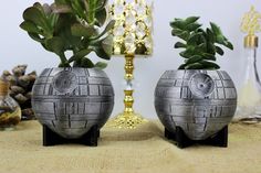 two star wars themed planters sitting on a table next to a vase with plants in it