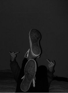 a woman sitting on top of a bed holding her hands up