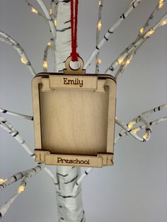 a wooden ornament hanging from a tree with lights on it's branches