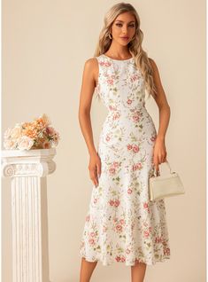 a woman in a white dress standing next to a vase with flowers and a purse