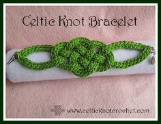 a green crocheted bracelet on a white piece of cloth with metal clasps