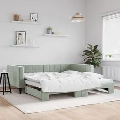 a living room with white walls and wooden flooring, including a couch that is made out of an upholstered mattress