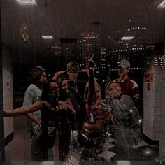 a group of people standing around each other in a room with mirrors on the wall