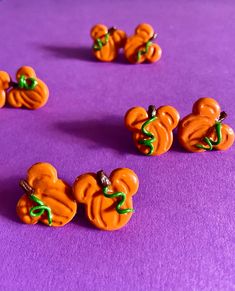 several orange buttons with green bows on them sitting on a purple surface in the shape of pumpkins