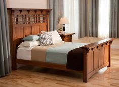 a wooden bed sitting on top of a hard wood floor next to a window covered in curtains