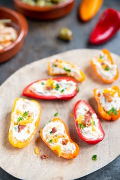 peppers stuffed with cheese and herbs on a cutting board next to other small bowls filled with vegetables