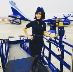 a woman in a black dress and hat standing on the stairs to an airplane