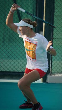 a woman holding a tennis racquet on top of a hard surface tennis court