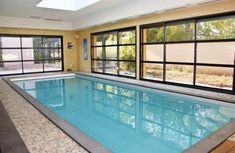 an indoor swimming pool surrounded by windows