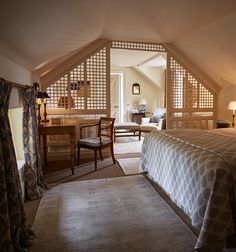 a bedroom with a bed, desk and chair in it's attic dormer