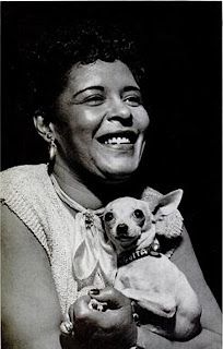 a black and white photo of a woman holding a small dog in her lap, smiling at the camera