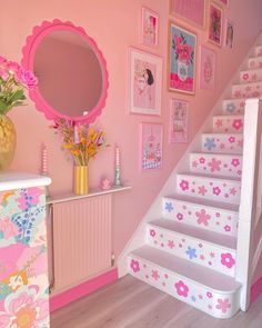 the stairs are decorated with pink flowers and pictures on the wall above them, along with a vase full of flowers