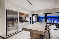 a modern kitchen with stainless steel appliances and marble counter tops, along with large sliding glass doors that lead to an outdoor deck