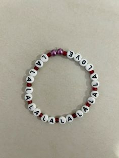 a white beaded bracelet with red beads and words that spell out one day at a time