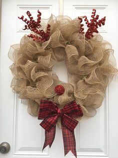 a wreath with red berries and burlocks hanging on the front door to welcome guests