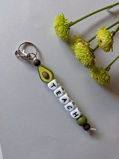 a keychain with the word teach on it next to some flowers and leaves