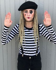 a woman with long blonde hair wearing a black and white striped shirt holding her hands up in the air