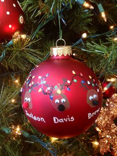 a christmas ornament hanging from the tree with reindeers on it's head