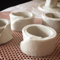 several white vases sitting on top of a table next to eachother with holes in them