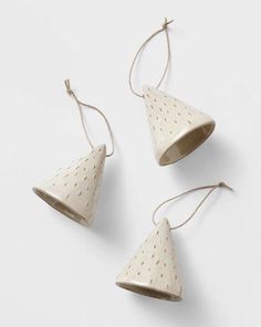 three white ceramic hanging lights with polka dot design on the top and one has a cord