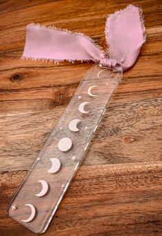 a pink ribbon tied to a piece of paper on top of a wooden floor with phases in it