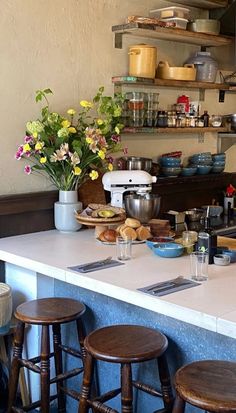 a kitchen counter with lots of food on top of it and flowers in vases