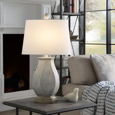 a table lamp sitting on top of a coffee table next to a fire place in a living room