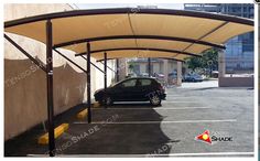 a car parked in a parking lot under a large awning over it's roof