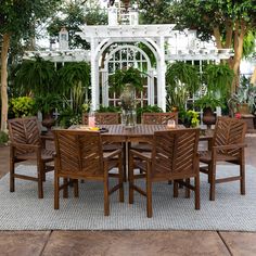 an outdoor dining table and chairs set up in front of a gazebo with potted plants