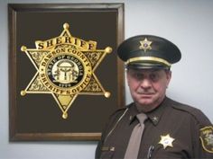 a police officer standing in front of a wall with a sheriff badge on it's chest