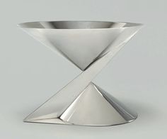 a silver vase with an x design on the top and bottom, sitting in front of a gray background