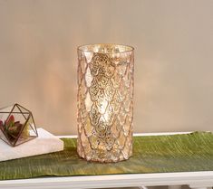 a glass vase sitting on top of a table next to a candle holder and napkin