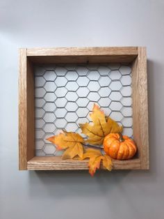 a wooden frame with some leaves and pumpkins on it