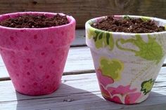 two flower pots with dirt in them sitting on a wooden table next to each other