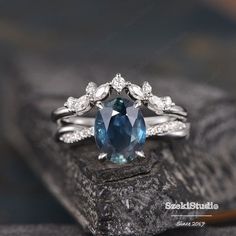 a blue and white diamond ring sitting on top of a rock