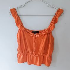 an orange top hanging on a white wall