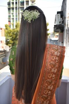 the back of a woman's head with long hair and flowers in her hair