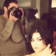 a woman taking a selfie in front of a mirror with a camera on her shoulder