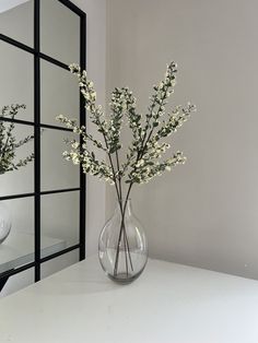 a vase filled with white flowers sitting on top of a table next to a mirror