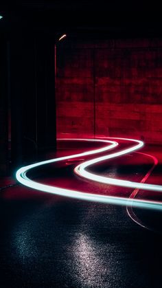 the light is streaking down the road in front of a brick wall and door