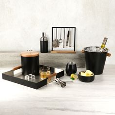 an assortment of kitchen utensils and drinks on a table with white walls in the background