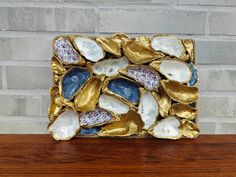 a gold and white shell sculpture sitting on top of a wooden table next to a brick wall