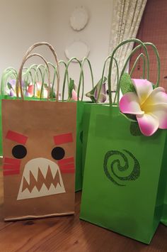 two paper bags with designs on them sitting on a table next to flowers and other decorations