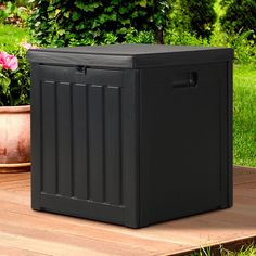 a black storage box sitting on top of a wooden deck next to potted plants