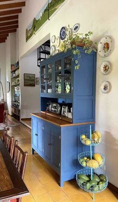 a kitchen with blue cabinets and plates on the wall, along with yellow tile flooring