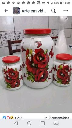 three vases with red flowers painted on them sitting on a counter next to each other