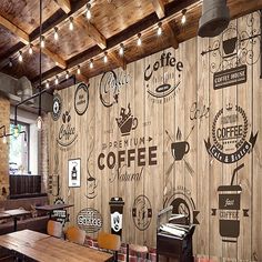 the interior of a coffee shop with wood paneling and wooden tables, chairs, and artwork on the walls