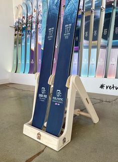 two skis are propped up on a stand in front of a wall with snowboards