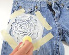 someone is cutting out paper with scissors and tape on their back pocket to make a flower