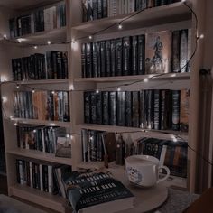 a bookshelf filled with lots of books next to a coffee cup on a table